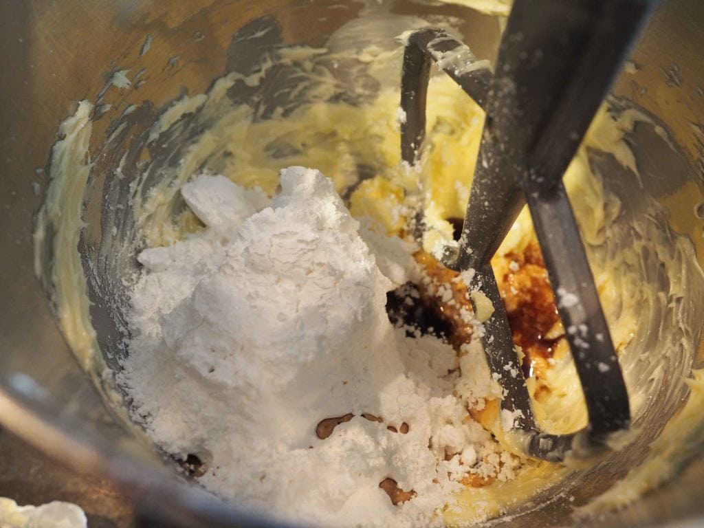 Mixing bowl with butter, vanilla, powdered sugar ready to blend. 
