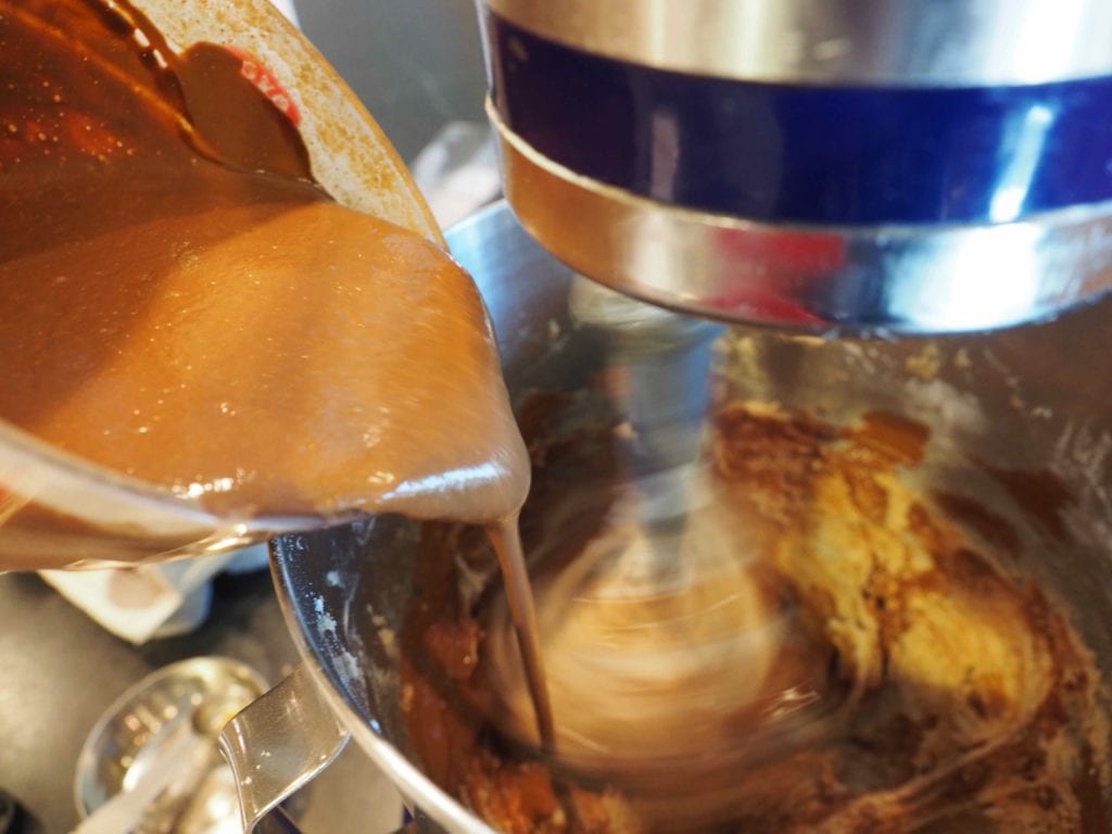 Pouring in sour cream and cocoa mixture into mixer