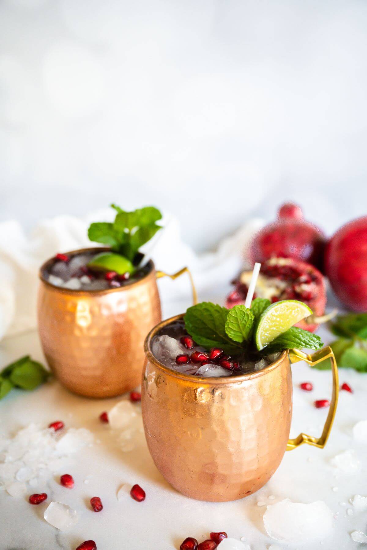 Best pomegranate moscow mule in copper mugs garnished with mint and limes.