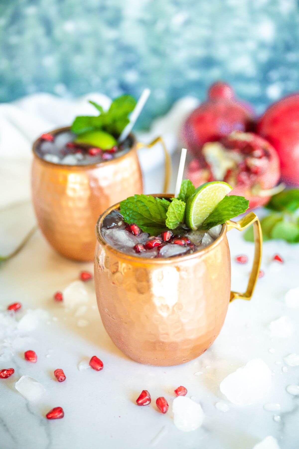 Two copper mugs filled with pomegranate Moscow mule.