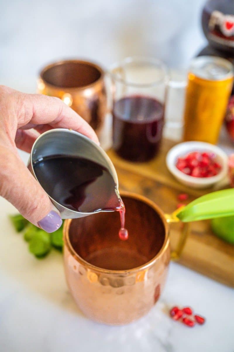 Pouring pomegranate juice into copper cup.