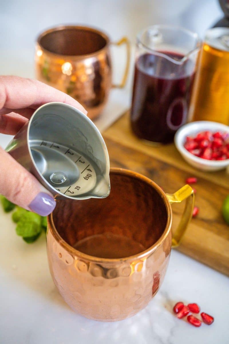 Pouring vodka into copper mug. 