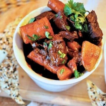 A bowl full of tender beef stew with carrots and potatoes.