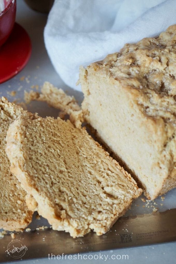 Close up of beer bread with two pieces sliced on a cutting board with serrated knife.