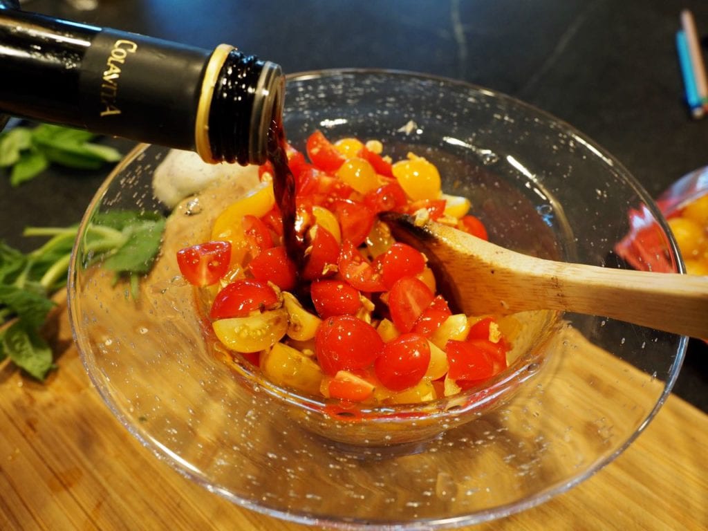  Pouring balsamic vinegar over garlic and tomato mixture