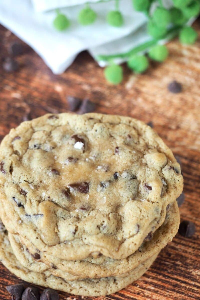 Stacked chewy chocolate chip cookies baked at high altitude on table.