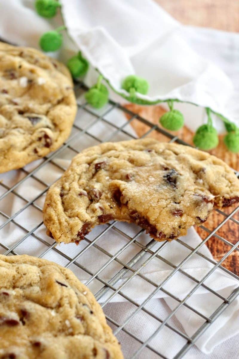 Thick and chewy chocolate chip cookies with bite take out, on cooling rack.