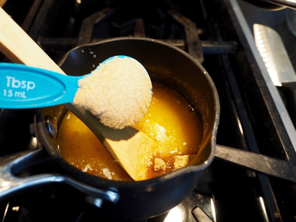 Adding a tablespoon of brown sugar to small pot on stovetop with wooden spoon in pot. Ham & Swiss Sliders | www.thefreshcooky.com