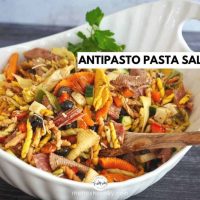 large white bowl of pasta salad with wooden spoon