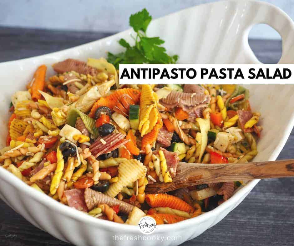 large white bowl of pasta salad with wooden spoon