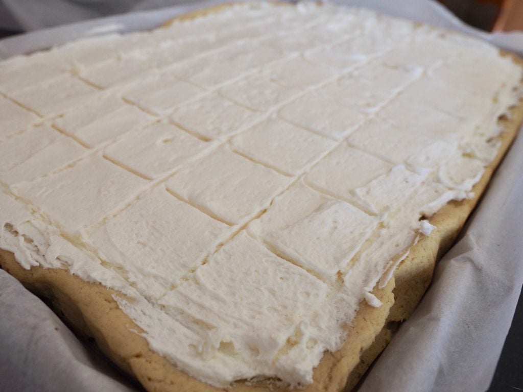 FROSTED sheet pan of sugar cookie bars, with frosting scored and ready for cutting.