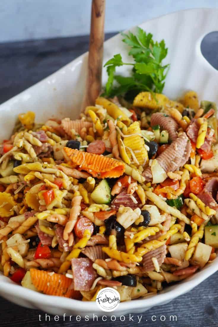 pasta salad in large white bowl with wooden spoon