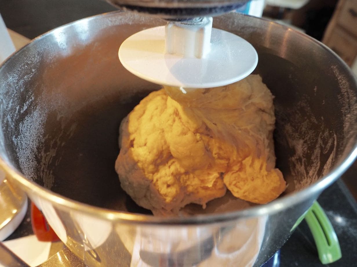 Cinnamon roll bread dough on J hook in mixer, being kneaded. 