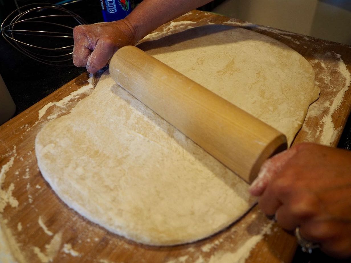 Rolling cinnamon bun dough on floured surface for cinnamon rolls.