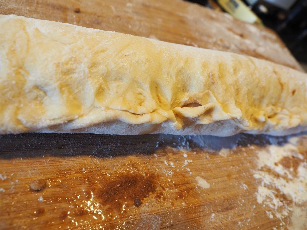 Pinching the seems together on cinnamon roll dough log. 