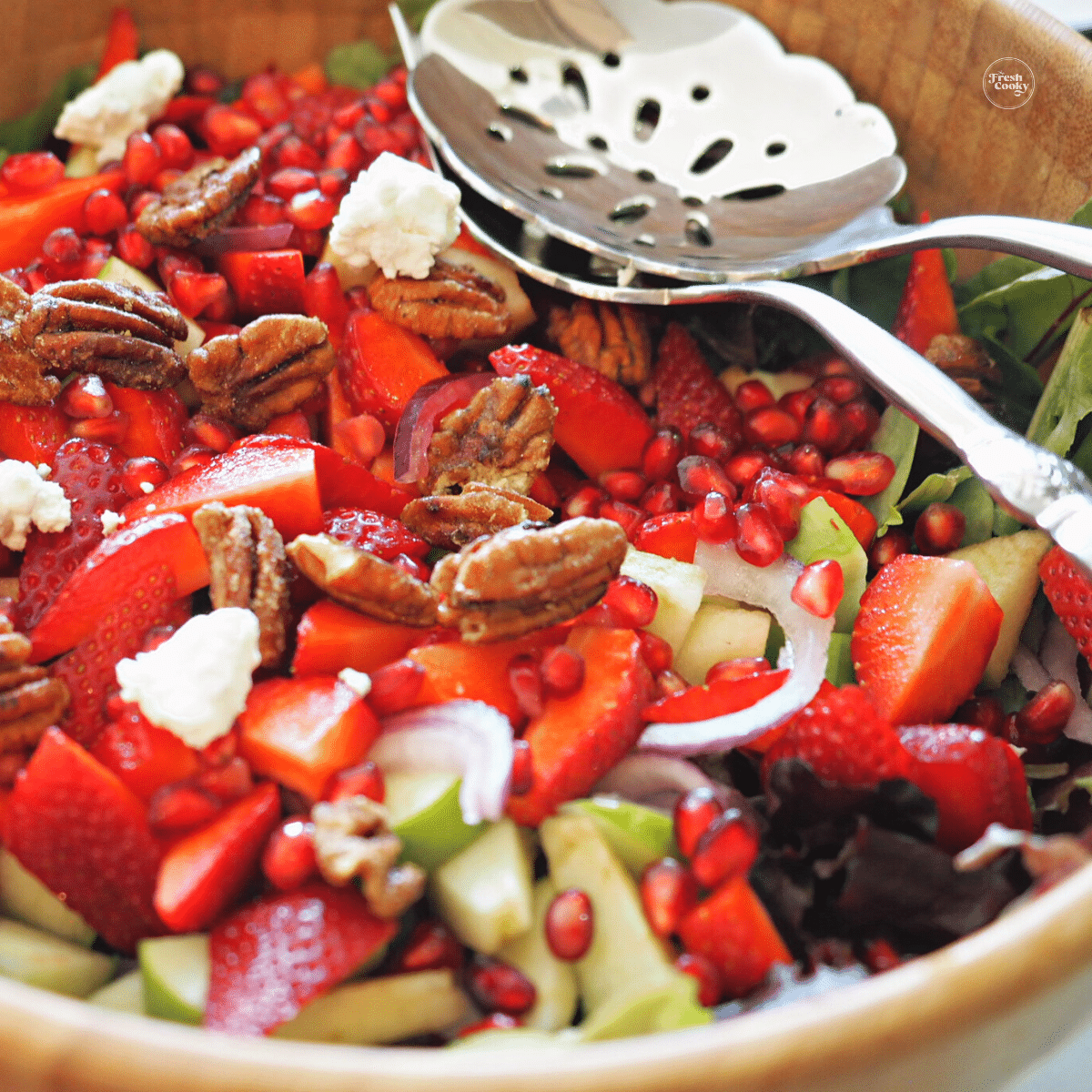 Sweet maple apple pecan salad in wooden bowl with serving spoons.