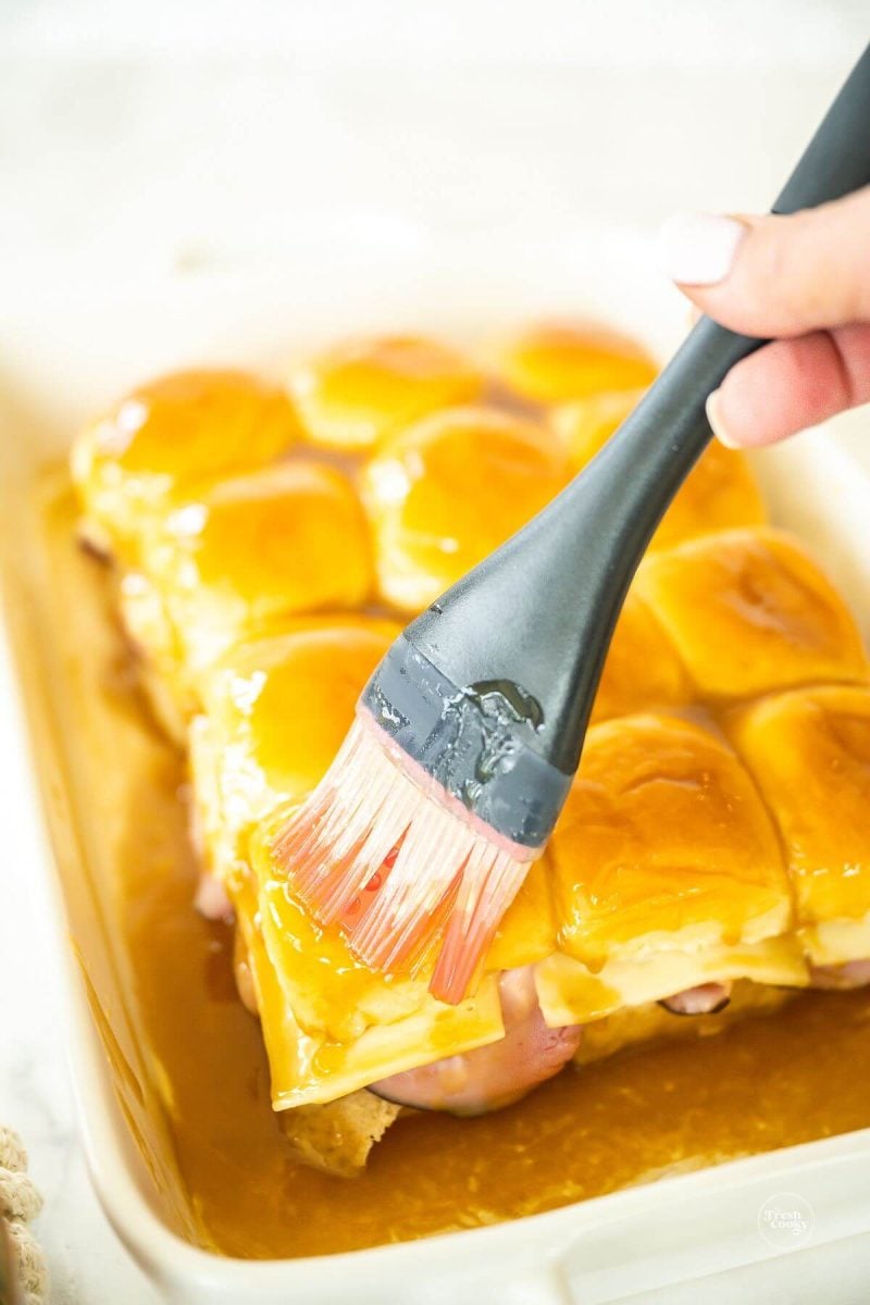 https://www.thefreshcooky.com/wp-content/uploads/2017/04/brushing-butter-sauce-on-ham-and-cheese-sliders-800x1200.jpg