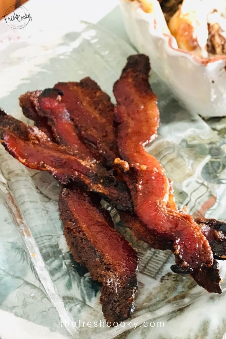 Candied bacon on pretty clear serving dish.