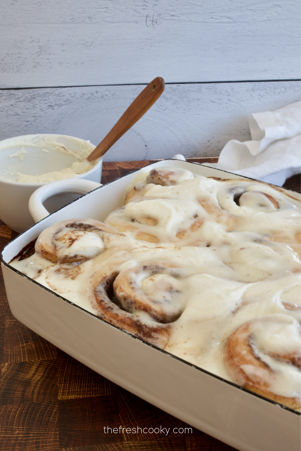 Image of a pan filled with soft, hot cinnamon buns covered in a thick layer of cream cheese cinnabon frosting.