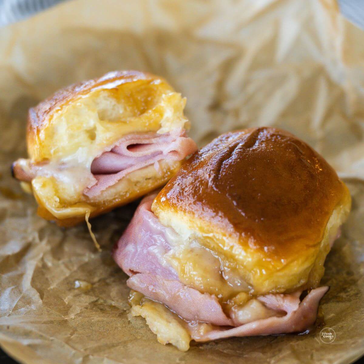Funeral Sandwiches on parchment, with hot ham, gooey Swiss cheese on Hawaiian rolls.