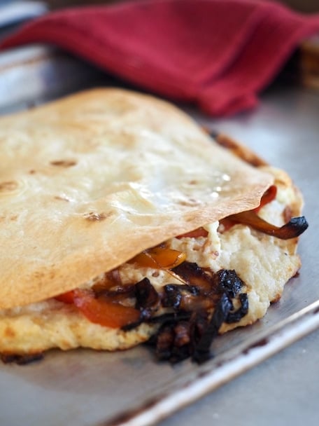 Half sheet baking pan with crispy flour tortilla, melting cheesy chicken mixture and caramelized and crispy onions and peppers | www.thefreshcooky.com