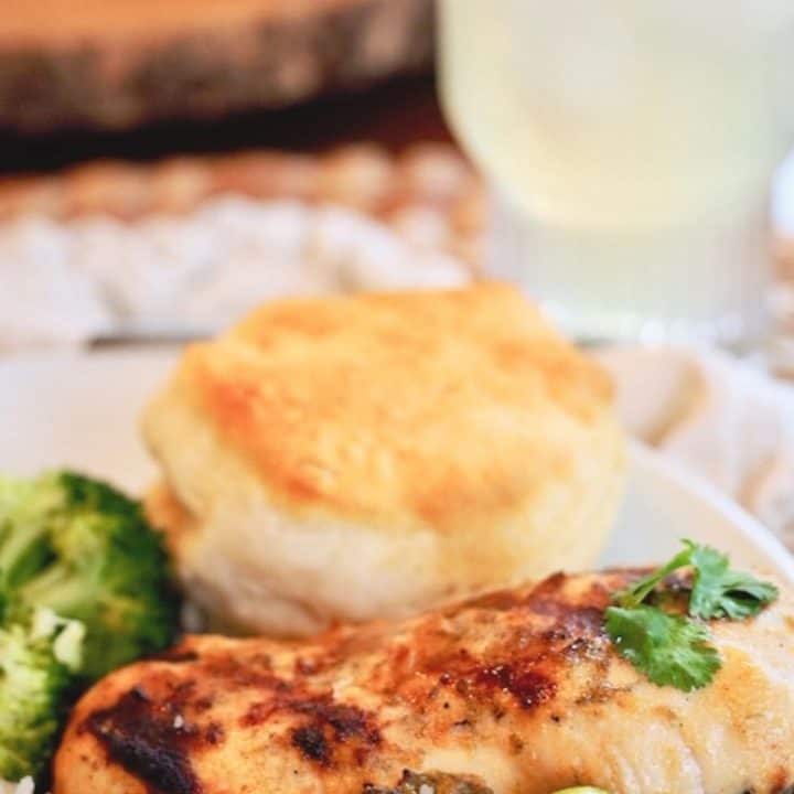 Best coconut lime chicken marinade with chicken breast, fresh lime, biscuit amd lemonade in background.