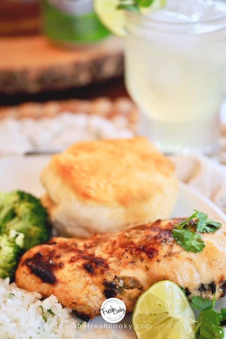 Best coconut lime chicken marinade with chicken breast, fresh lime, biscuit amd lemonade in background.