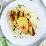 Coconut lime chicken on a plate of cilantro lime rice garnished with a lime and cilantro.