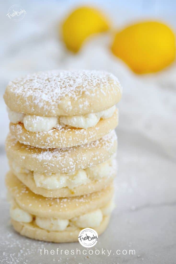Stack of lemon shortbread sandwich cookies with dusting of powdered sugar.