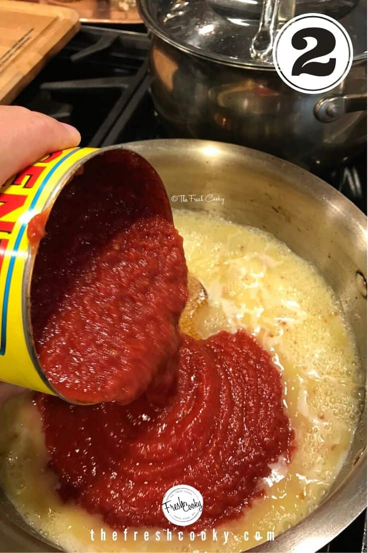 pouring crushed tomatoes into vodka butter sauce in pan