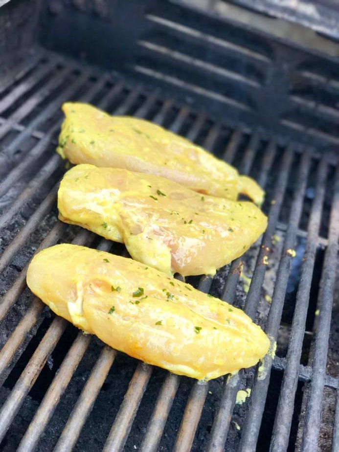 Chicken breast that has been marinated in thai coconut marinade, sitting on hot grill. 