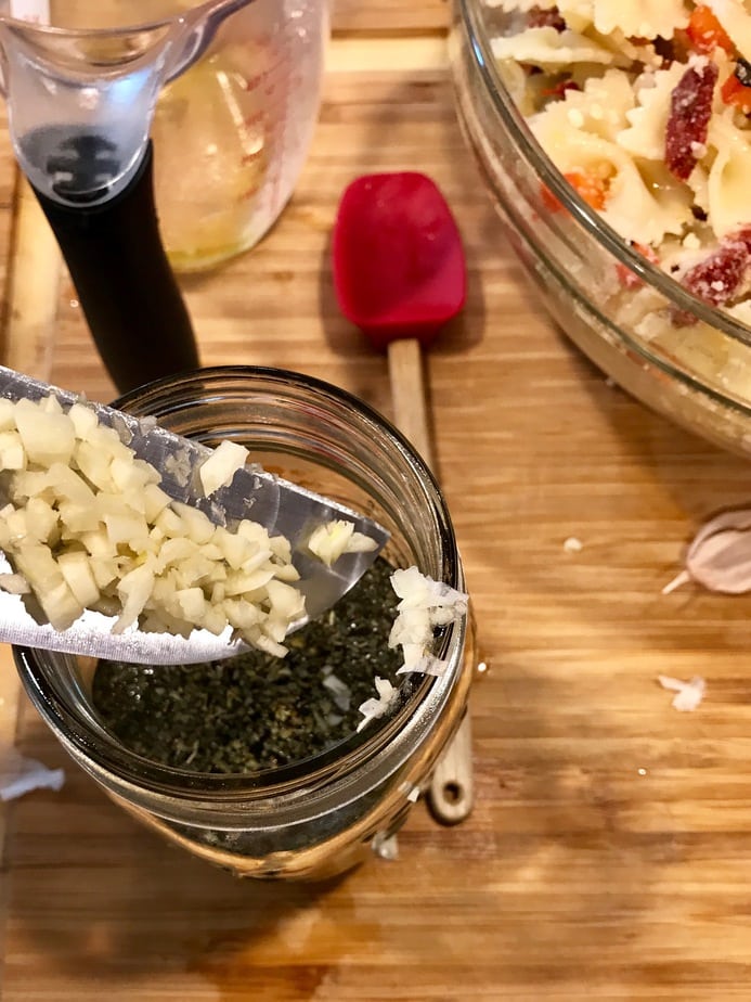  Adding chopped garlic to dressing jar. 