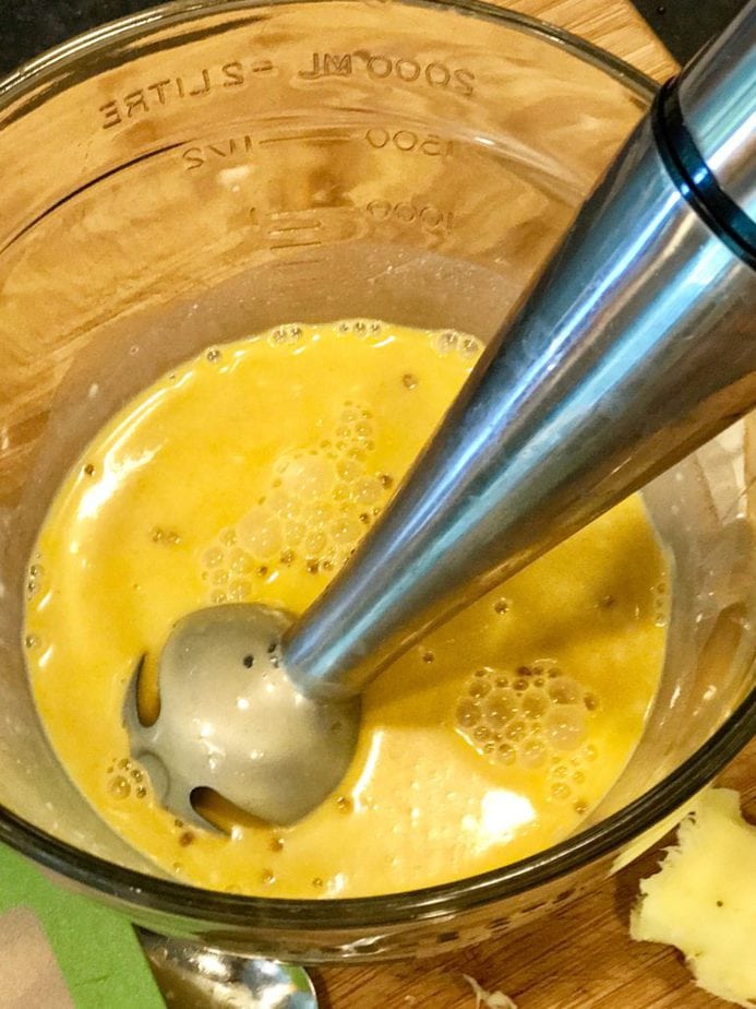 Immersion blender blending coconut milk, spices and ginger and garlic. 