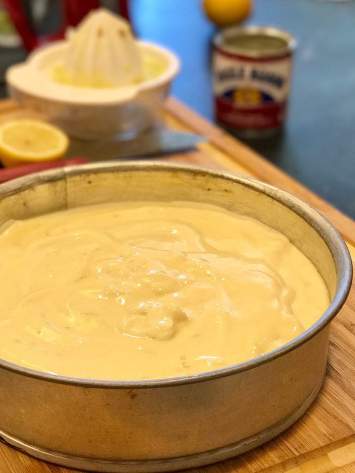 Key lime batter poured into spring form baking pan on a cutting board