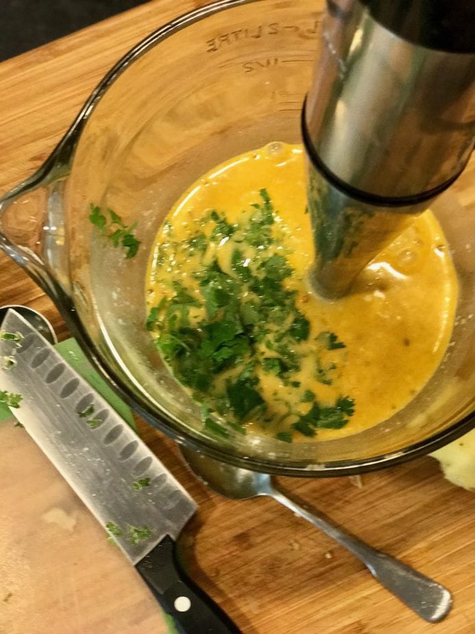 immersion blender mixing cilantro into coconut milk mixture. 