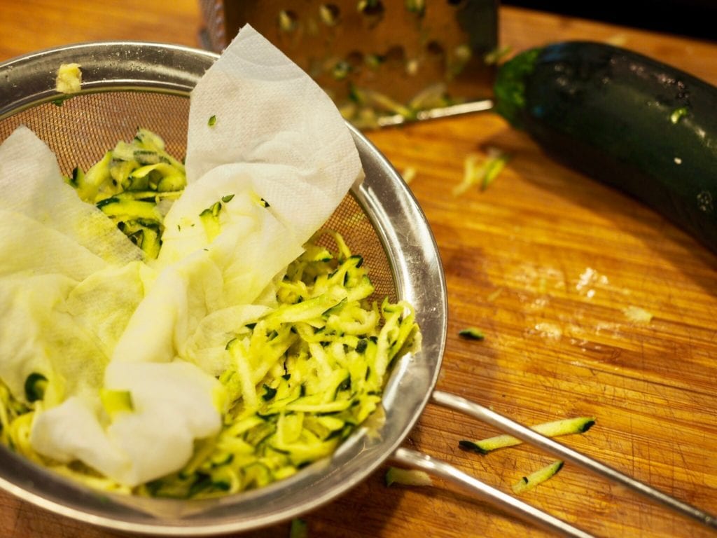 Squeezing water from zucchini using mesh strainer | www.thefreshcooky.com