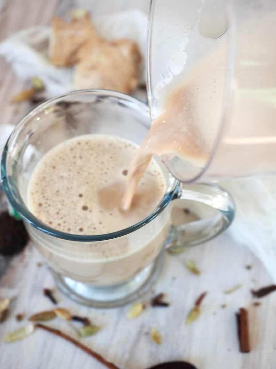 Pouring hot chai tea latte with ingredients in background | thefreshcooky.com