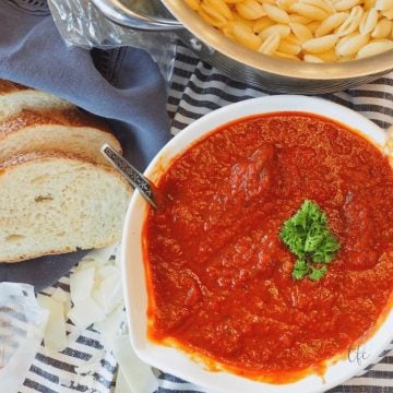Bowl filled with easy pasta sauce with pasta and bread nearby.