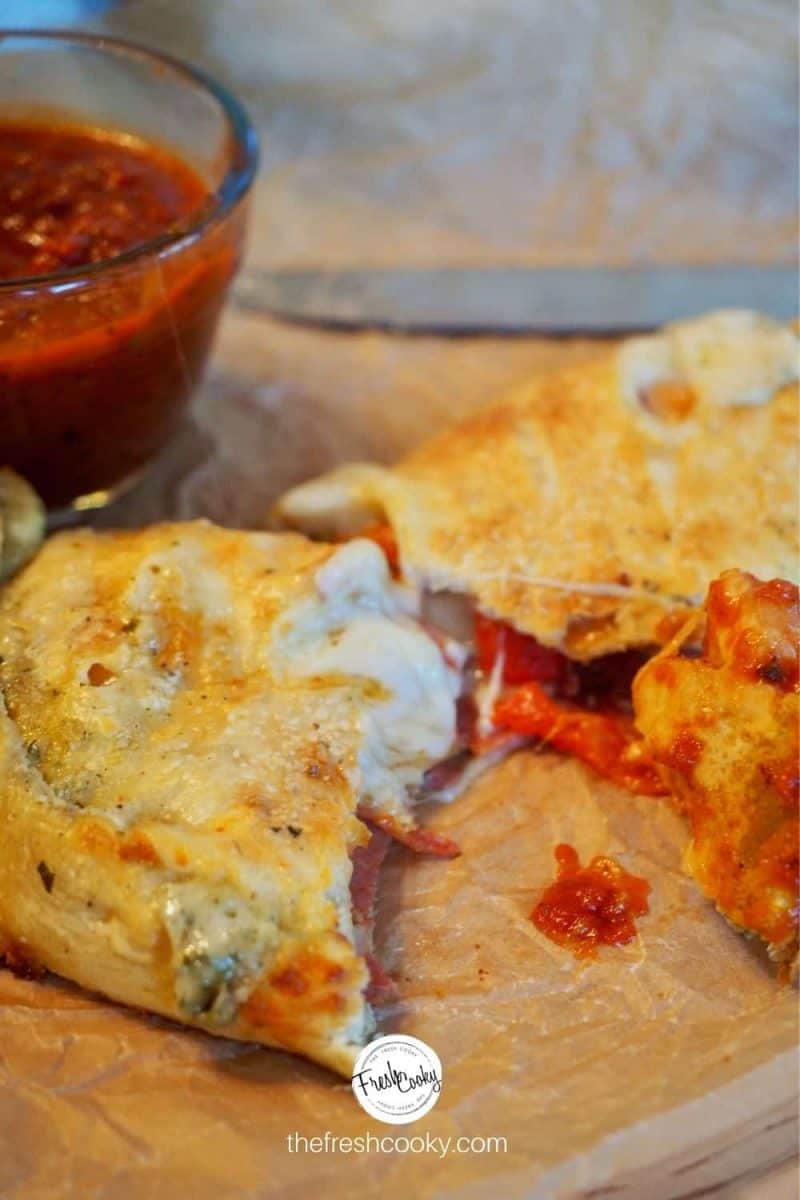 Sliced in half pizza easy calzone with dipping sauce, knife in background