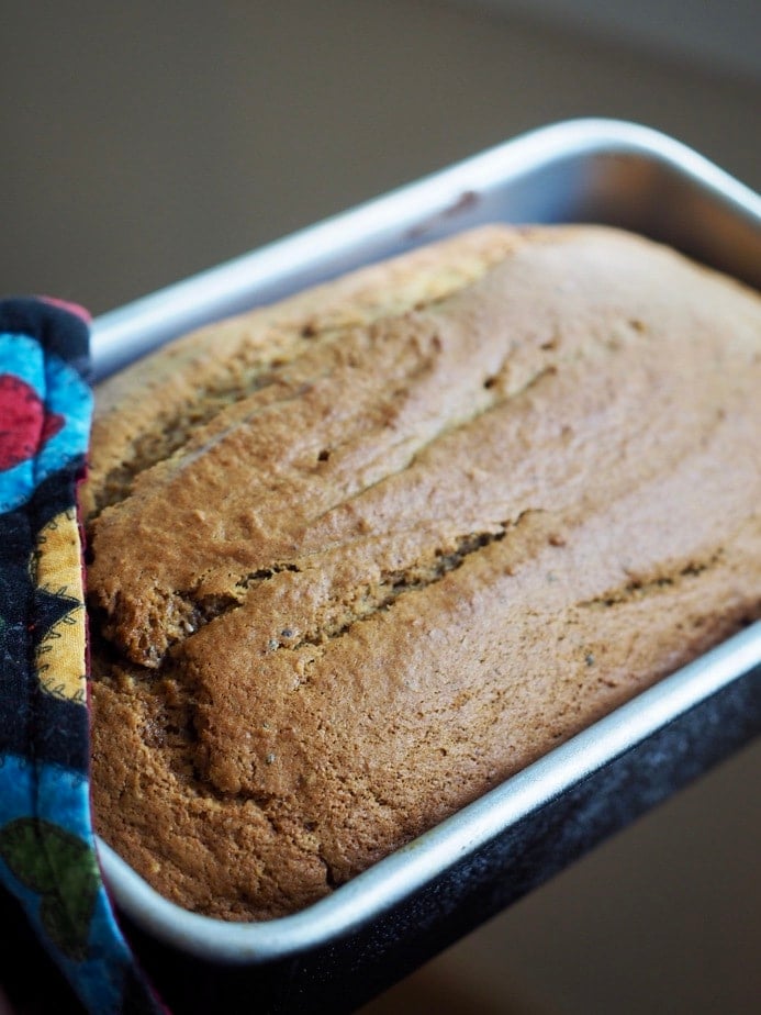 Oven mitt holding just out of the oven moist pumpkin bread in loaf pan. 