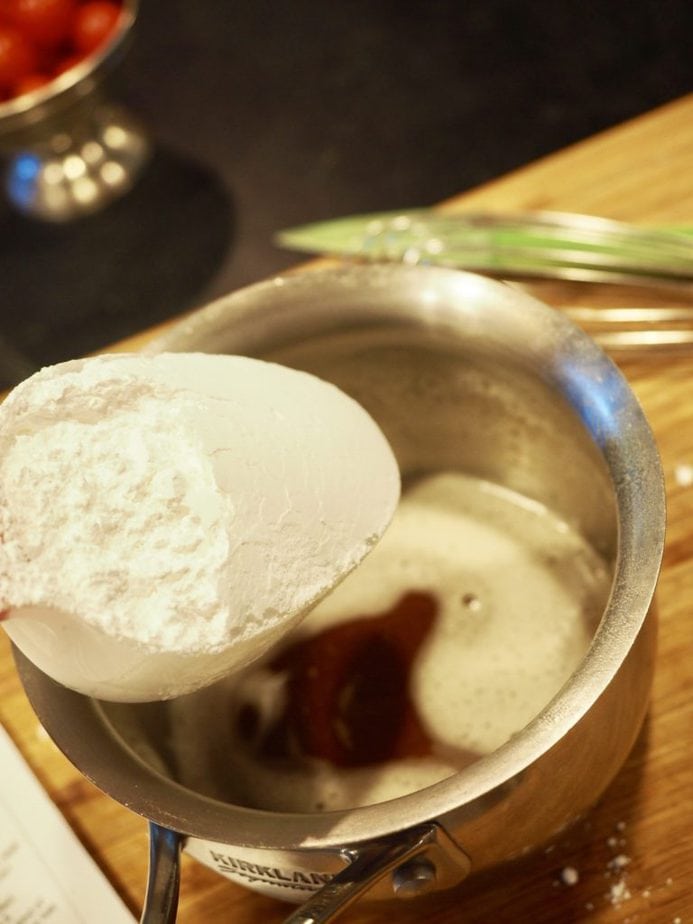 Adding powdered sugar to browned butter for topping moist pumpkin bread.