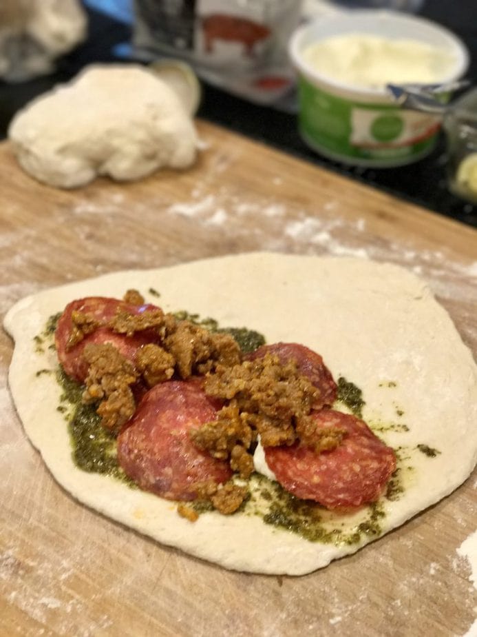 Pizza dough spread with pesto, ricotta, Italian sausage and pepperonis for easy Calzones