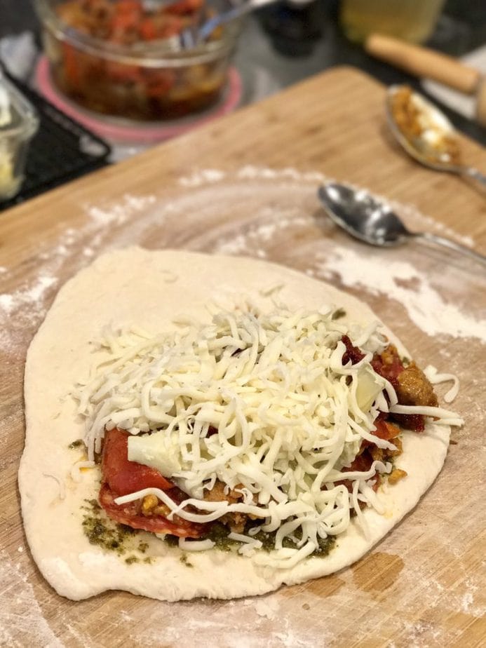 Adding mozzarella cheese and artichoke hearts fore easy calzones on cutting board. 