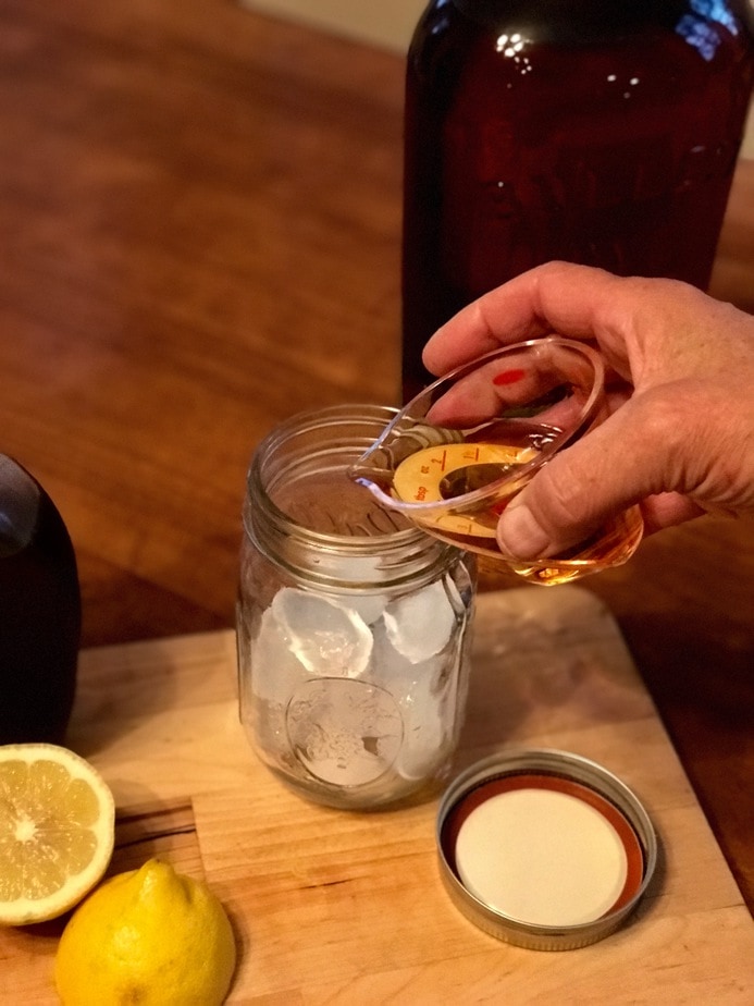 Pouring whisky into mason jar with ice.