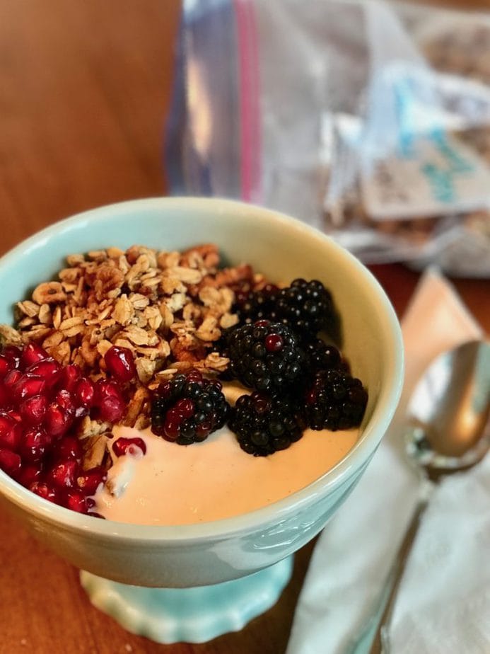 Footed bowl with yogurt parfait, blackberries, pomegranates and soft granola. 