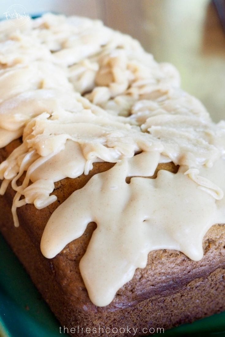 Loaf of moist pumpkin bread with a brown butter maple frosting drizzled on top.