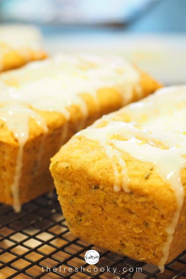 Mini loaves of lemon zucchini bread dripping with lemon glaze atop a cooling rack.