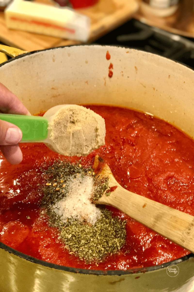 Adding sugar and spices to Italian spaghetti sauce.