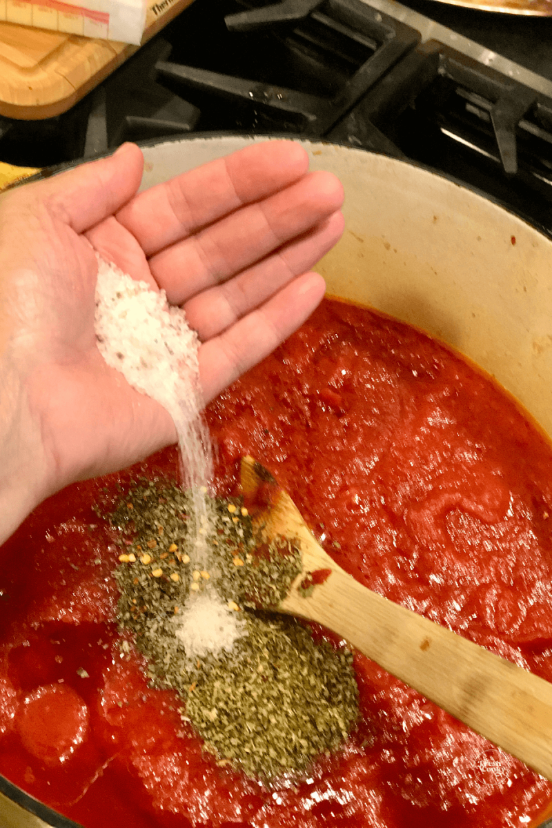 Adding salt into Italian spaghetti sauce. 