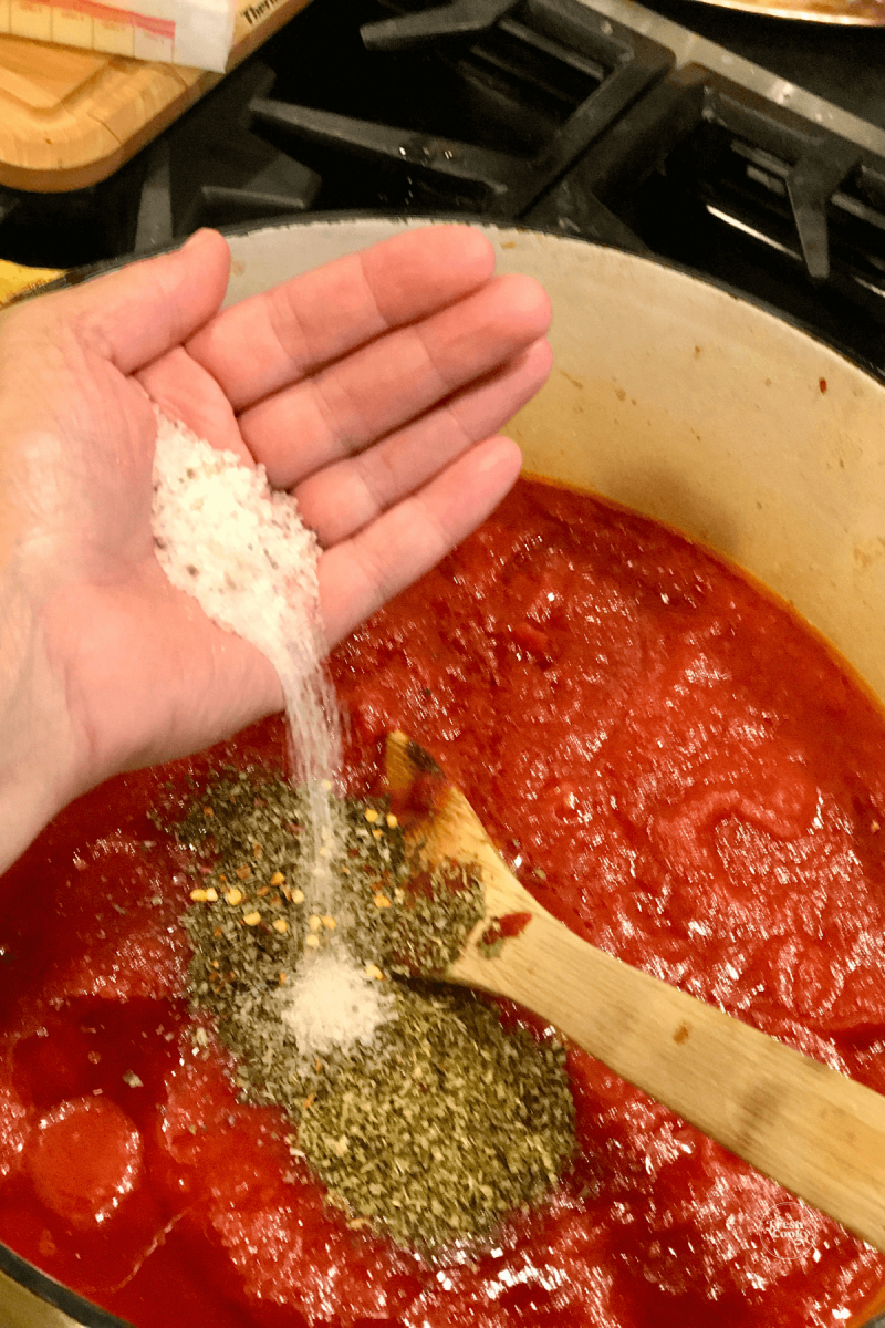 Adding salt into Italian spaghetti sauce.